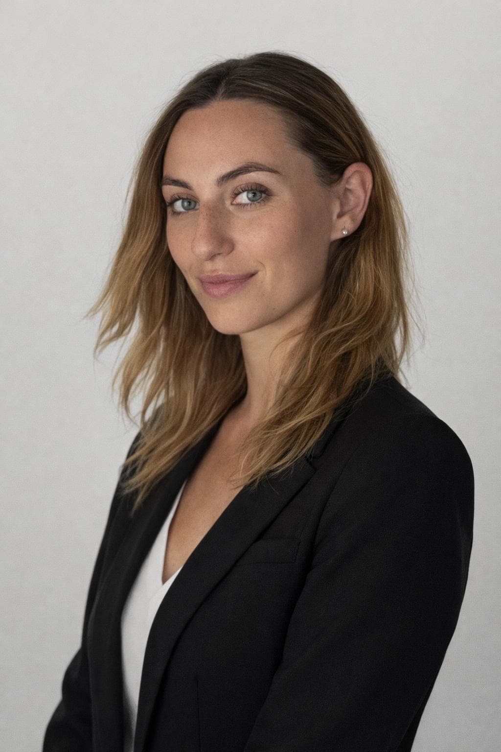Professional headshot of a smiling woman with light brown hair wearing a black blazer.